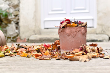 flowerpot  put on the floor of a terrace and full of dry leaves with autumnal colors