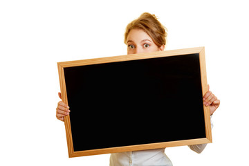 Woman hiding shyly behind blackboard