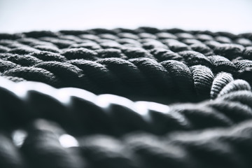 Close up of black battle rope on a gray backgound. Sport and fitness equipment.