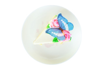 Top view piece of vanilla cake decorated with butter cream, pink rose and blue butterfly on dish isolated on white background.