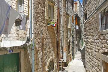 Historic narrow street with stone made houses and laundry on lines, Sibenik, Croatia