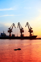 Obraz premium Gantry crane and cargo ship in the evening