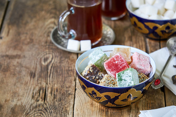Turkish delight in a bowl and black tea on a wooden background