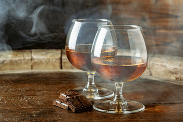 Two glasses of bourbon or scotch, or brandy and pieces of dark chocolate