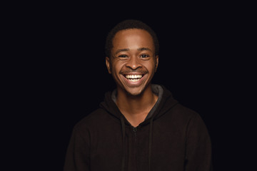 Close up portrait of young african-american man isolated on black studio background. Real emotions...
