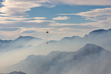 Helicopter flying high over mountains during wildfire