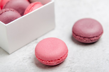 Pink macaroon cookies on a stone background in box. The concept of sweets, pastries, junk food. Minimal composition.