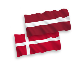 National vector fabric wave flags of Latvia and Denmark isolated on white background. 1 to 2 proportion.
