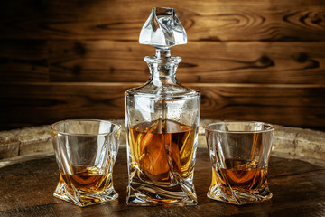 Two glasses of brandy or cognac and bottle on the wooden table