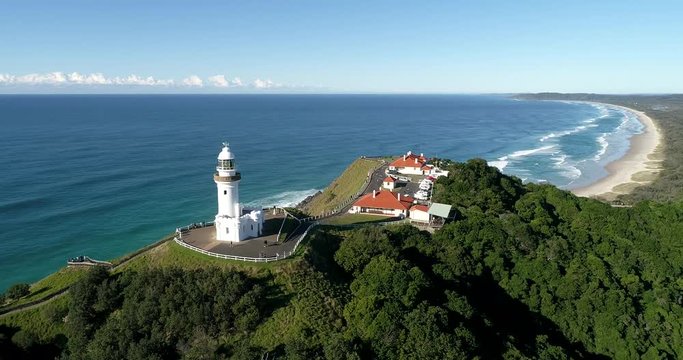 White tower of Byron Bay lighthouse on the top of Headland covered by green woods on Pacific coast.