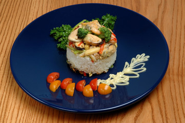 Risotto with seafood with decor. Restaurant dish. On a blue plate and on a wooden background