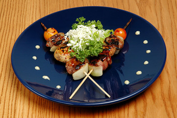 Mini kebab of zucchini and meat on a blue plate, on a wooden background. Restaurant dish, appetizer with vegetables