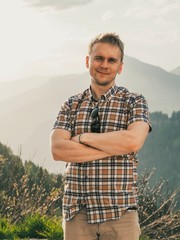 A young man in a plaid shirt stands against the background of the Dolomites. Mountain summer landscape in the Dolomites in Northern Italy.