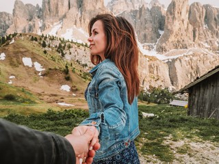 Fototapeta premium Brunette girl with long hair holding the hand of a man and leads him to the mountainsMountain summer landscape in the Dolomites in Northern Italy. Aerial view of National Park Tre Cime di Lavaredo.