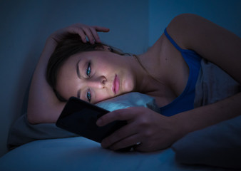 Attractive woman addicted to mobile phone late at night in bed l