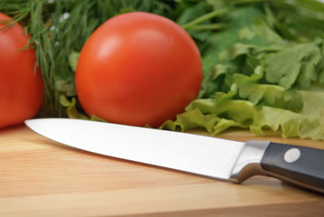 Chopping board with tomato, parsley and knife