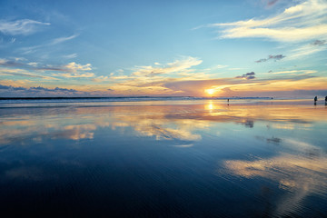 Beautiful sunset on ocean beach. Sky is reflecting at water.