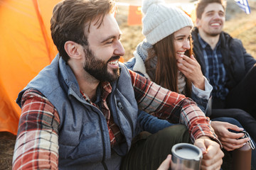 Group of cheerful young friends camping outdoors