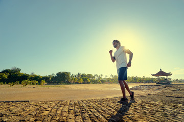 Sports lifestyle. Happy young african man jogging on the sea shore.