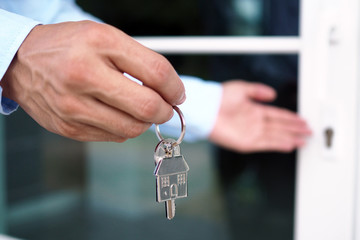 The hand of the banker holds the house key. Home and land mortgage concept