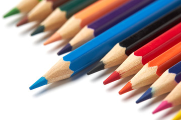Blue pencil stands out from a raw of other colored pencils lying on an isolated white background