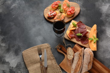 Brushetta or traditional Spanish tapas. Appetizers with Italian antipasti snacks. Variety of small sandwiches with cherry tomatoes, salmon, cream cheese. Prosciutto served with melon and basil
