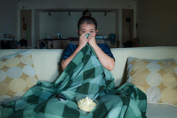  young beautiful scared and frightened Asian Korean woman watching horror scary movie or thriller...