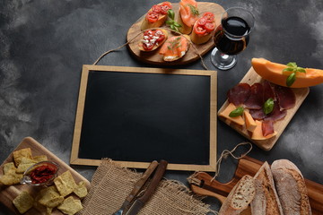 Brushetta or traditional Spanish tapas. Appetizers with Italian antipasti snacks. Variety of small sandwiches with cherry tomatoes, salmon, cream cheese. Prosciutto served with melon and basil