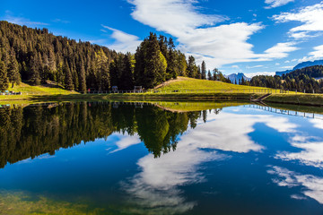 The small pond reflects the sky and clouds