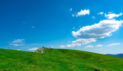 Landscape of green grass and rock hill in spring with beautiful blue sky and white clouds. Countryside or rural view. Nature background in sunny day. Fresh air environment. Stone on the mountain.