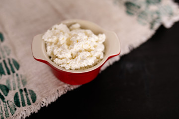 dairy product cottage cheese in brown ceramic bowl with spoon on vintage wooden table