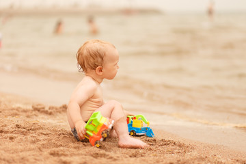 Little kid playing with sand on sea beach.
