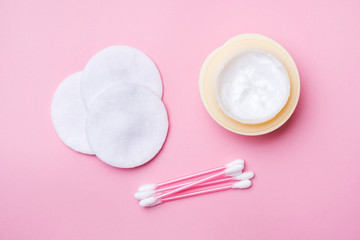 Pink cotton swabs and cotton swabs and a can of cream on a pink background. Selective focus Copy space.