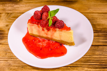 White plate with cheesecake New York, leaf of mint and raspberries on wooden table
