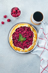 Homemade raspberry open pie gallete with cup of coffee on a light concrete table background. Top view, copy space