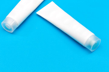 Beauty cosmetics tube; branding mock up; top view on blue background. Package for hand cream or scrub. Beauty cosmetics tube; branding mock up; top view