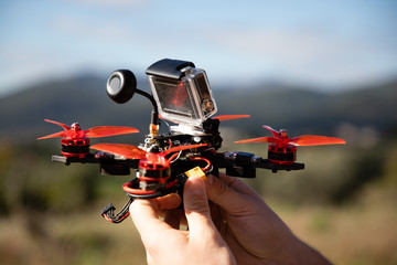 Hands holding a fpv racing drone with action camera