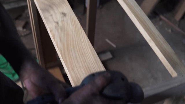 A man making wooden surface smooth and even with the help of a sanding machine
