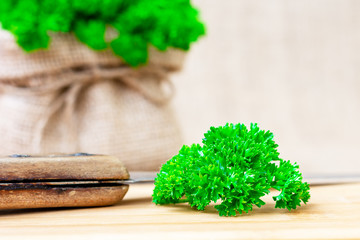 Close-up on a bundle of fresh green parsley on a wooden cutting board with a knife. Healthy vegetarian and vegan food ingredient. Latin name Petroselinum from family Apiaceae.