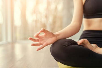 Crop woman meditating on floor