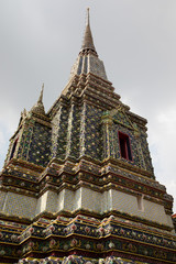 Fototapeta premium Side view of the pagodas of a temple in Bangkok with cloudy sky as background