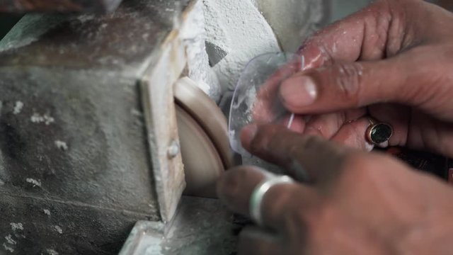 Close up video of a worker using a small grinding machine for polishing glass for specs