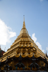 Fototapeta na wymiar Low angle view of a golden pagoda from the Emerald Buddha Temple with white and clouds in the background