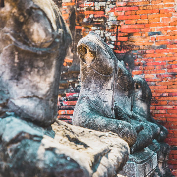 Close up of ancient stone buddha statues placed in line in the ruined temple at Ayutthaya