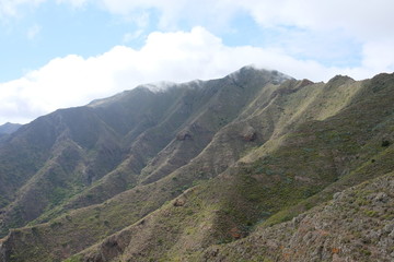 Fototapeta na wymiar Clouds over green volcanic mountain cliffs