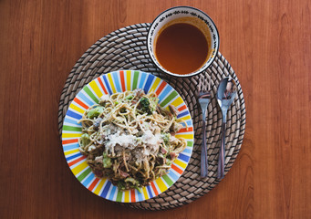 Carbonara spaghetti on colorful plate and gazpacho on bowl all on wooden table