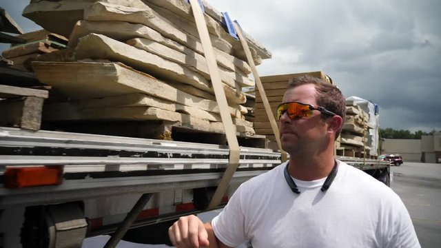 Slow motion shot of trucker checking load of building stone