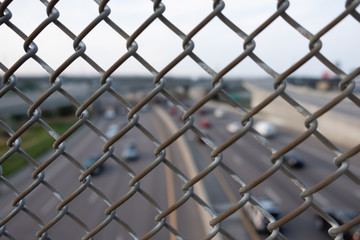 Fototapeta premium Blurred highway view through a metallic fence