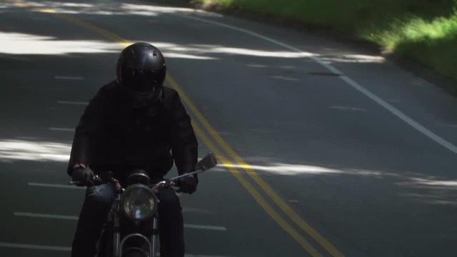 Motorcyclist With Leather Jacket Coming to a Stop on a Wooded Road