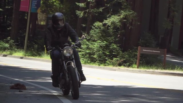 Slow Motion of Motorcyclist With Leather Jacket Riding on a Wooded Road